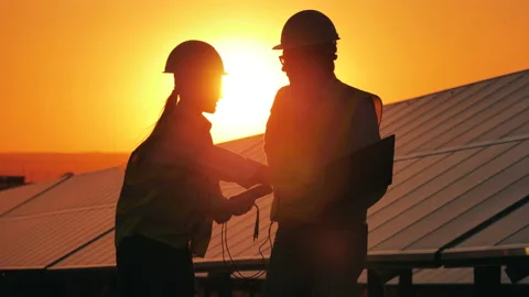 Two power workers are talking next to sunlit solar batteries Video stock 140971022