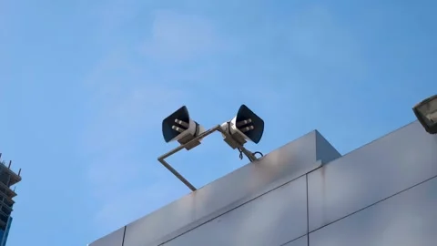 Two powerful loudspeakers are positioned high on the edge of a building  库存影片 333325988