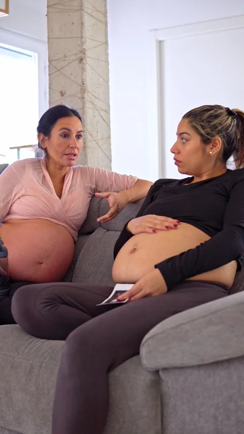 Two pregnant women talking while looking at an printed ultrasound of one of her  Stock Footage 284458338