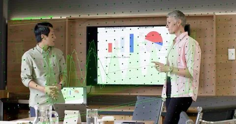 Two presenters tapping remote and pointing at bar and pie charts, tracing Stock Photos