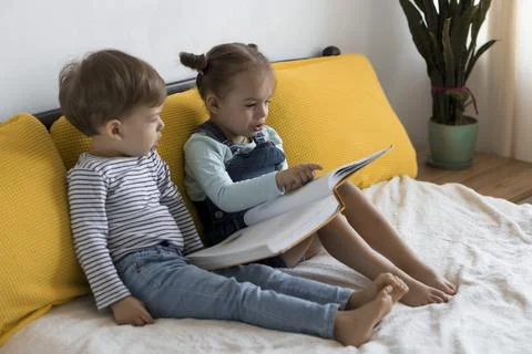 Two preshool, toddler children read large interesting book of fairy tales on Stock Photos