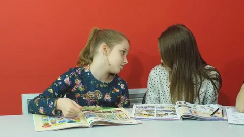 Two pretty friends discussing something in copybook at lesson Stock Footage 70585353