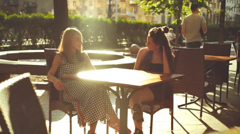 Two pretty girlfriends laughing while sitting in a bar outdoors Stock Footage 66261439