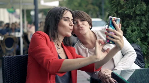 Two pretty girlfriends taking selfie photo with cellphone in cafe in city  Video stock 68167338