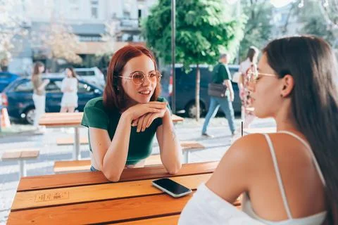 Two pretty girlfriends talking while sitting in a bar outdoors Foto stock