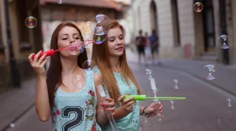 Two pretty girls having fun and blowing bubbles. Urban background. Stock Footage 55142444