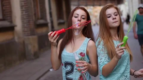 Two pretty girls having fun and blowing bubbles. Urban background Stock Footage 55142686
