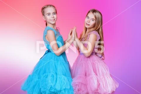Two pretty little girls dressed in beautiful festive dresses. Kid's fashion c Stock Photos