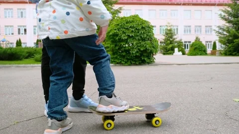 Two pretty little sisters having fun together learning to skateboard outdoors on Stock Footage 280210146