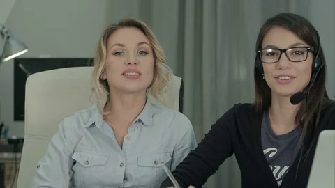 Two pretty managers presenting their company and services talking to the camera 스톡 동영상 71129034