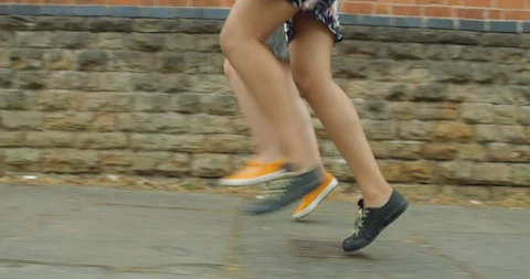Two Pretty Mixed Race Young Girl Twins Skipping Together Along a Street. Stock Footage 94549925