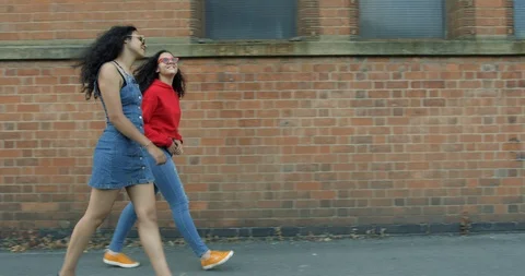 Two Pretty Mixed Race Young Sisters Walking Together Along a Street. Stock Footage 94552359