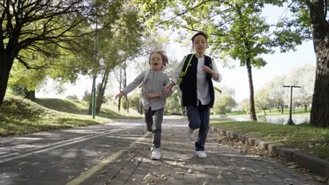 Two primary school boys with backpacks running to school after spending recess Stock Footage 140083366
