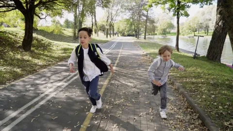 Two primary school boys with backpacks running to school after spending recess Stockbeeldmateriaal 140083462