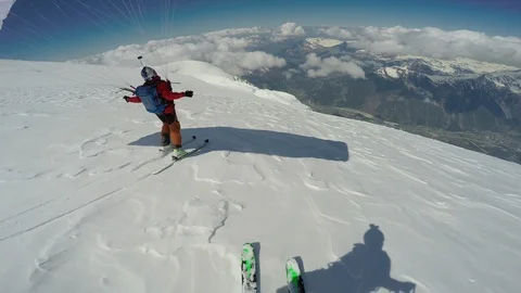 Two pro skiers freeriding on steep slope with parachutes on sunny day, Aspen Stock Footage 129129999