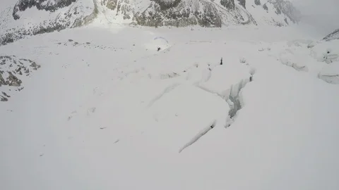 Two pro skiers parachuting over snowy mountains on cloudy day, Colorado Video stock 129131141