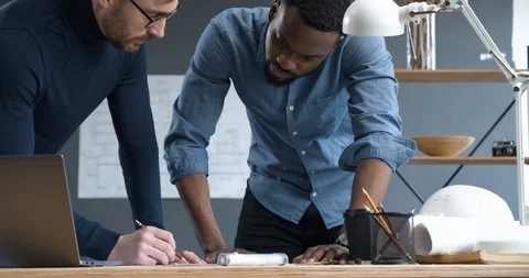 Two professional Architects go over blueprints in industrial Office, discussing Stock Footage 126161935