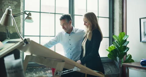 Two professional architects go over blueprints for a house in modern industrial Stock Footage 199461614