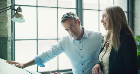 Two professional architects go over blueprints in modern industrial office durin Stock Footage 199461794