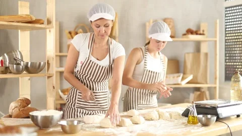 Two professional bakers work with pieces of raw dough. Bakery workers prepare Stockbeeldmateriaal 320448328