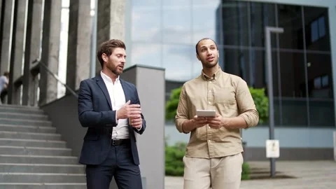 Two professional businessmen communicate while walking outside near office  Stock Footage 303414133