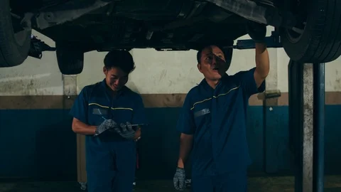 Two professional car mechanic using paperwork makes the oil and engine check. Video stock 122747537