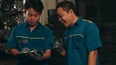 Two professional car mechanic using paperwork makes the oil. Video stock 153796457