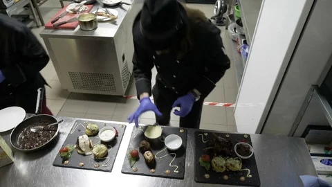 Two professional chefs in restaurant kitchen placing food on three black plat Stock Footage 81259278