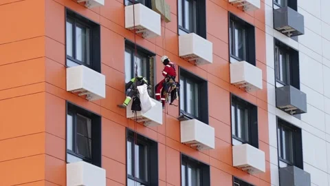 Two professional climbers perform repair work to insulate the window on the Stock Footage 278843537