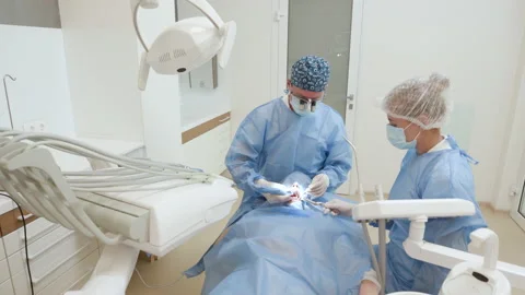 Two professional doctors doing dental surgery installing dental implants into Video stock 194461886