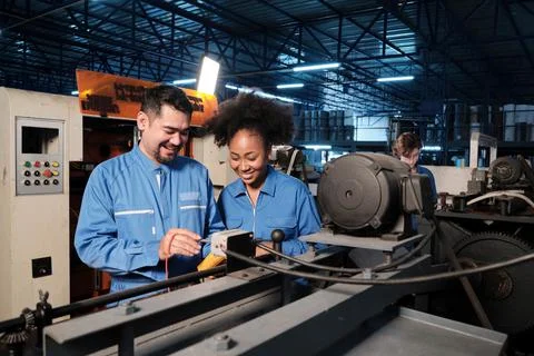 Two professional engineers inspect machines' electric systems at the factory. Stock Photos