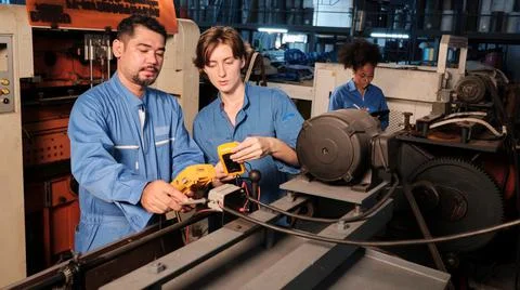 Two professional engineers inspect machines' electric systems at the factory. Stock Photos