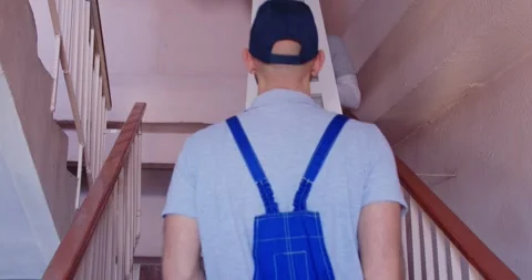 Two professional male movers lifting shelf up stairs with care ensuring safe Stock Footage 320807058
