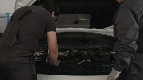 Two Professional Mechanics Inspecting Car Engine and Discussing Ignition Problem Stock Footage 329409970