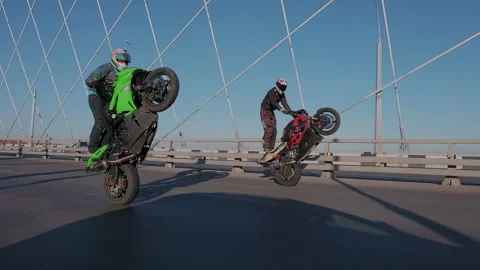 Two professional motorcyclists synchronously riding the rear wheels of the Stock Footage 105011098