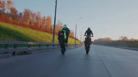 Two professional motorcyclists synchronously riding the rear wheels of the Stock Footage 105012626