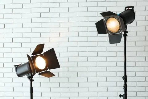 Two professional studio lights with barn doors on stands illuminating a white Stock Photos