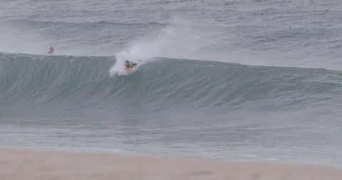 Two professional surfers getting carried away by rolling ocean waves in Peniche Stock Footage 159830901