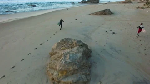 Two professional surfers running with surfboards on sandy beach near ocean Stock Footage 163051678