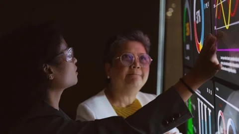 Two professionals analyze data on a large touchscreen, pointing at dashboard Stock Footage 319526241
