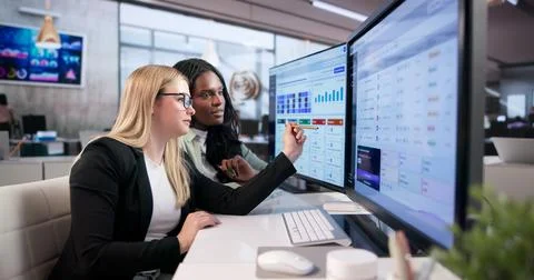 Two Professionals Analyze Risk Matrix Data On Computer Screens Together. Stock Photos