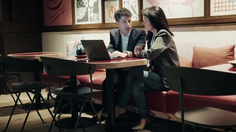 Two professionals at a cafe working with laptop in a modern urban setting 库存影片 304539159