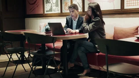 Two professionals at a cafe working with laptop in a modern urban setting 库存影片 304539168