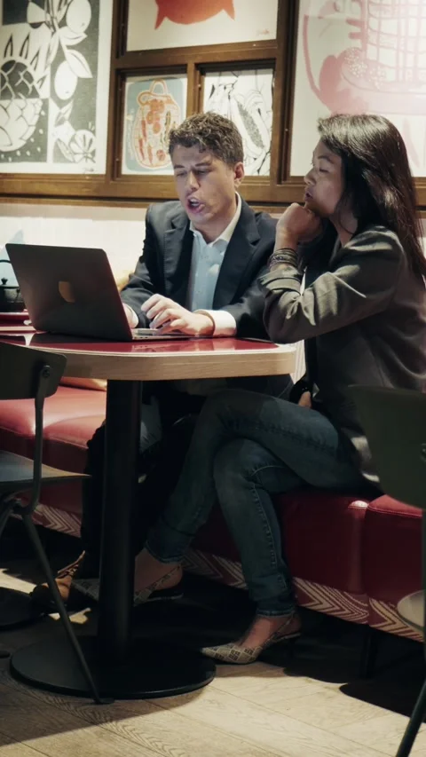 Two professionals at a cafe working with laptop in a modern urban setting Stock-Footage 305982672