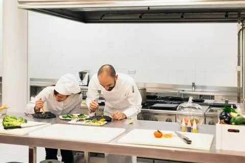 Two professionals chefs cooking together. Stock Photos