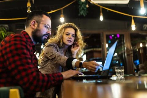 Two professionals collaborating on a project at a cozy cafe, with a focus on Stock Photos