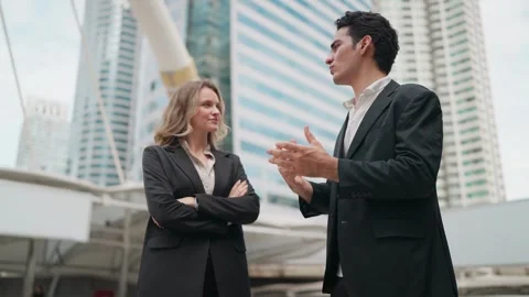 Two professionals converse under modern city skyscrapers Vídeo Stock 345198401