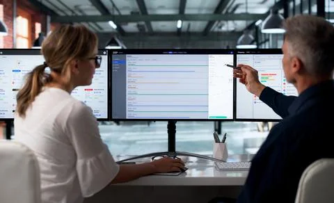 Two Professionals Discuss Integrated Cloud Software Solutions On Desktop Moni Stock Photos