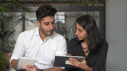 Two Professionals discussing project,showing details on tablet, writing notes. Vidéo 149574901