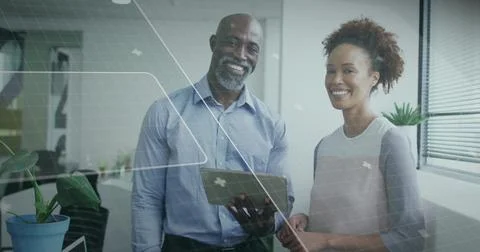 Two professionals holding tablet and pointing stylus in modern office, with Stock Photos